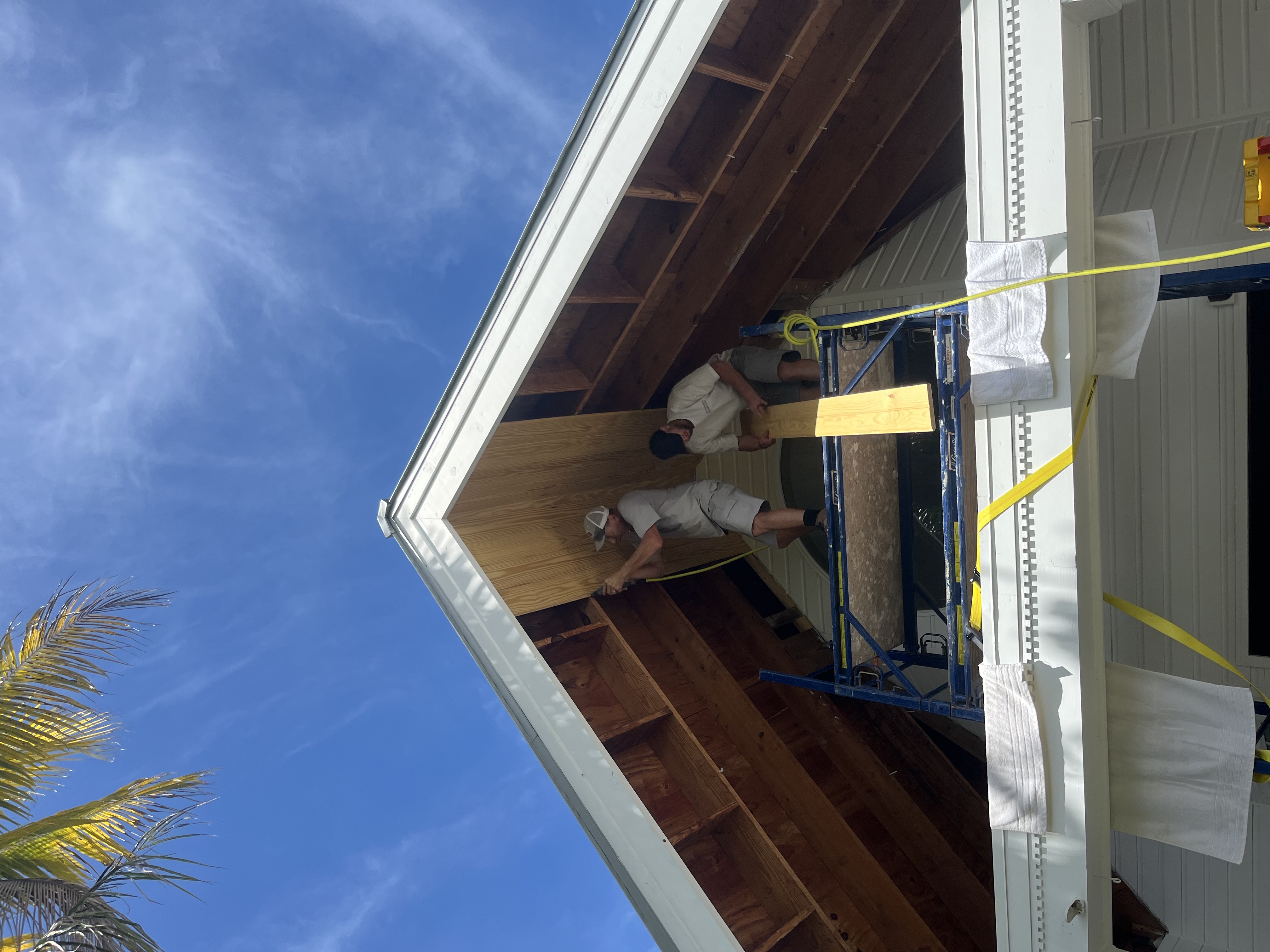 RD crew lifting the first tongue and groove boards into place inside the front entry gable