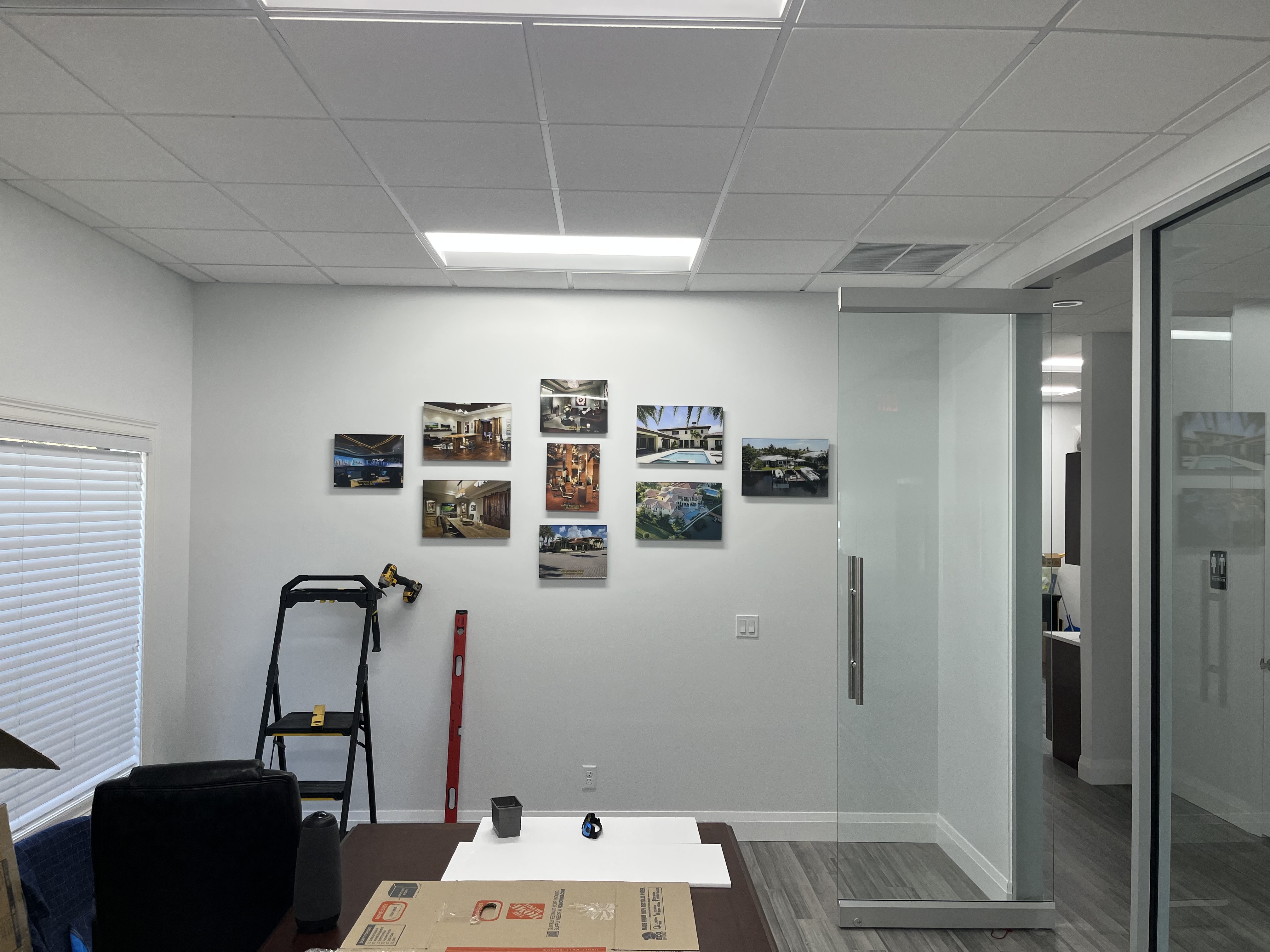 Conference room wall with multiple framed pictures evenly hung in a clean office setting