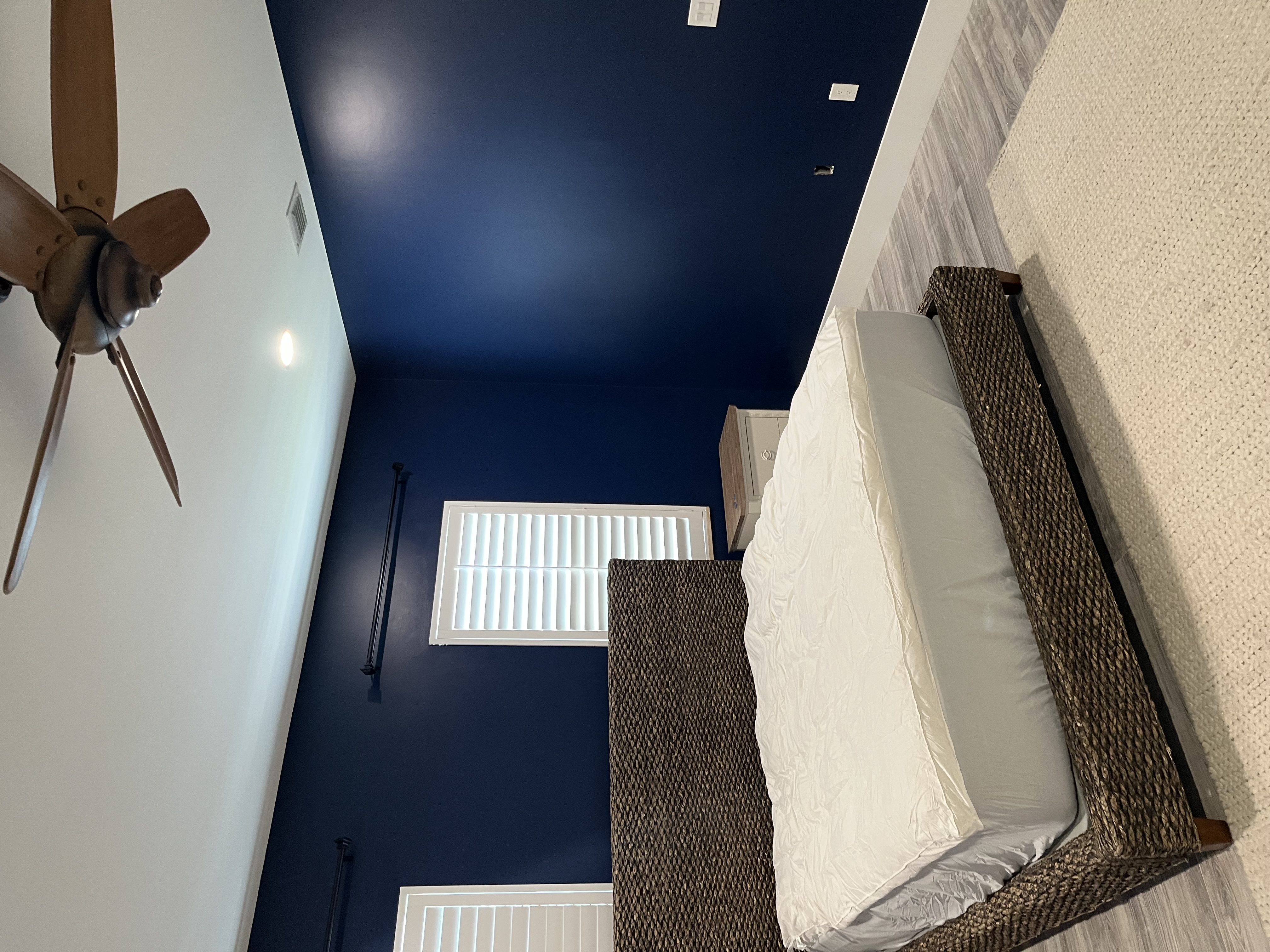 Finished bedroom painting job with deep blue walls shown beside the dresser and bed