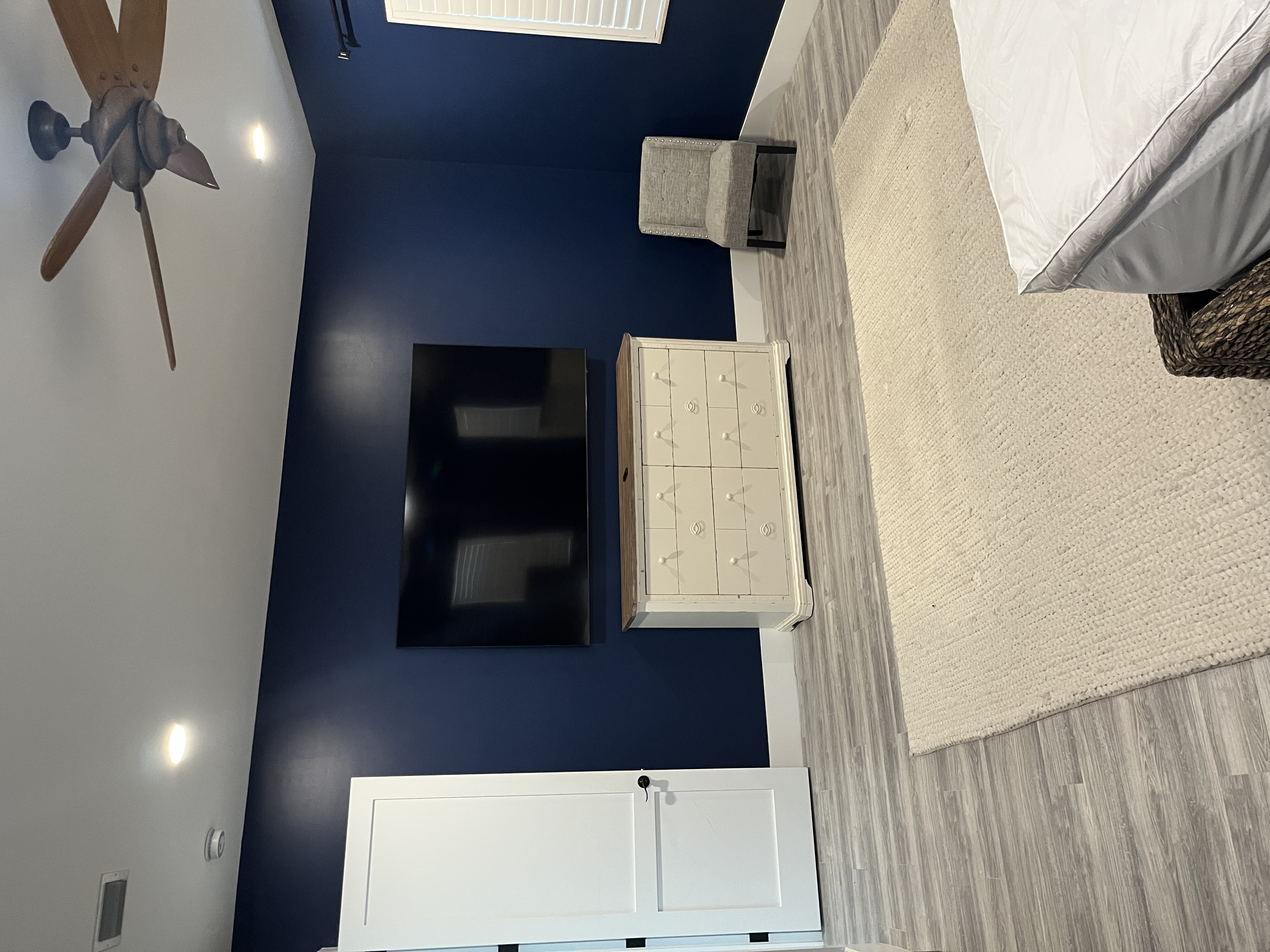Finished bedroom painting job featuring the dark blue wall behind the mounted television and dresser