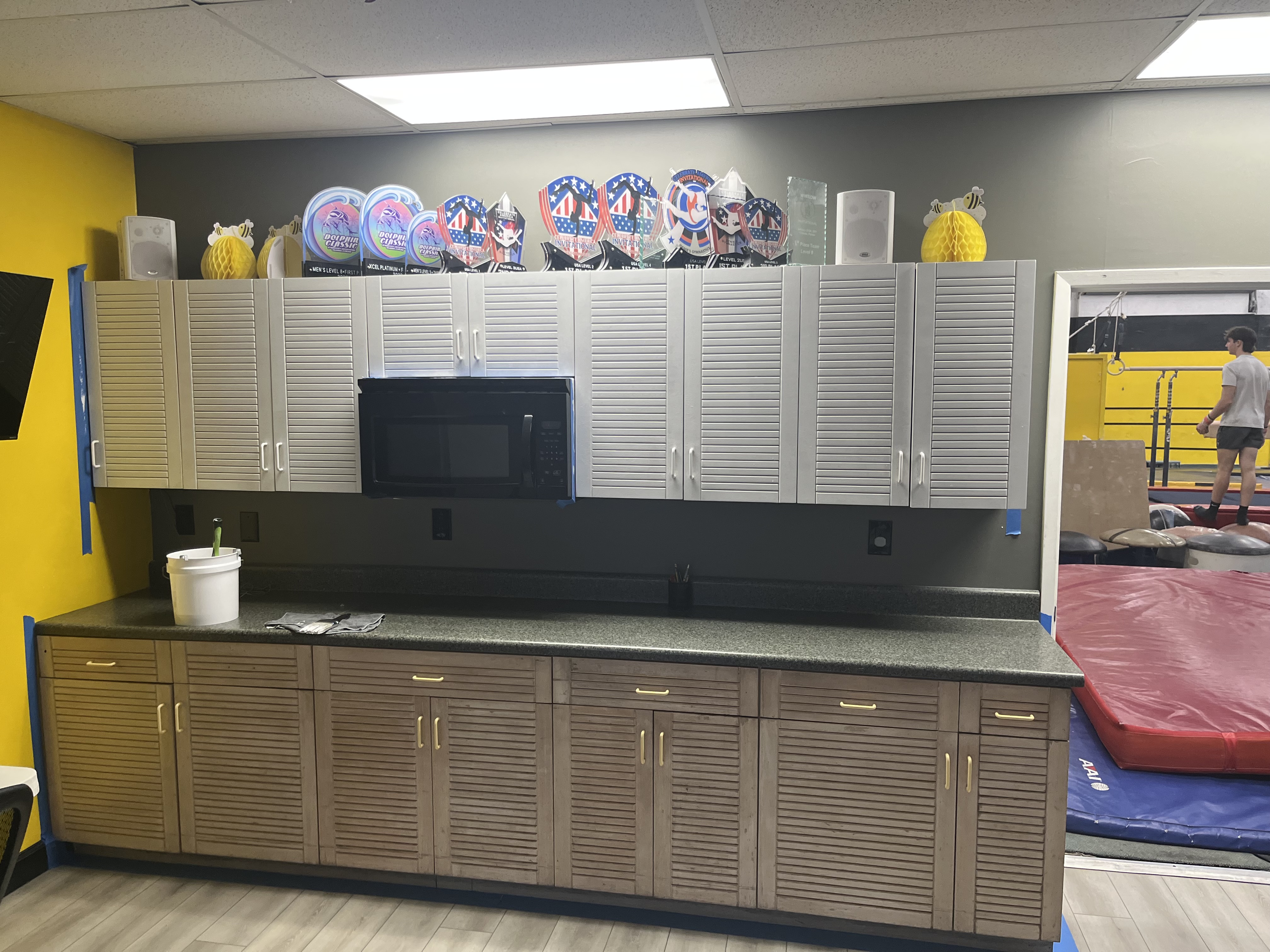 Gymnastics gym cabinet repaint in progress with the upper doors painted white semi-gloss