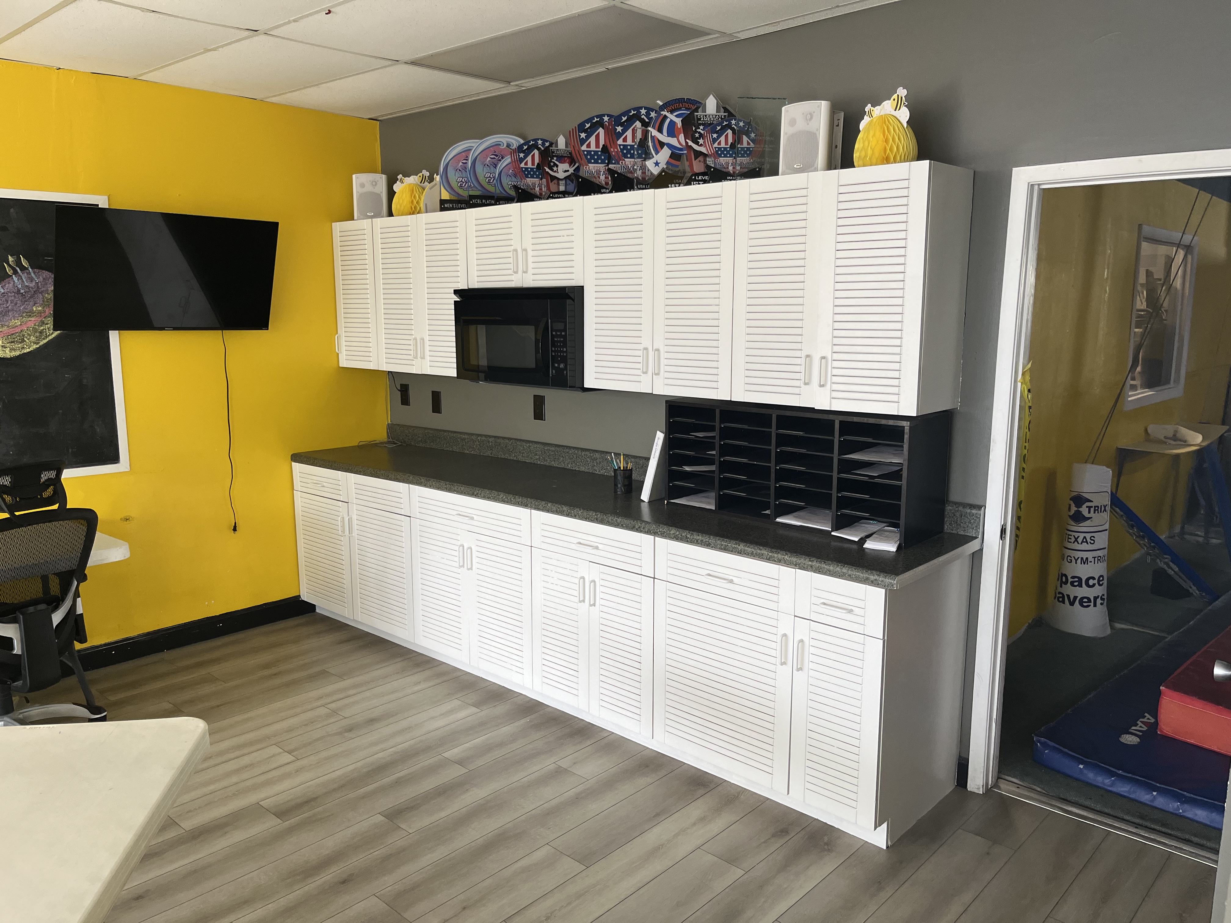 After photo of the completed white semi-gloss cabinet repaint in a gymnastics gym