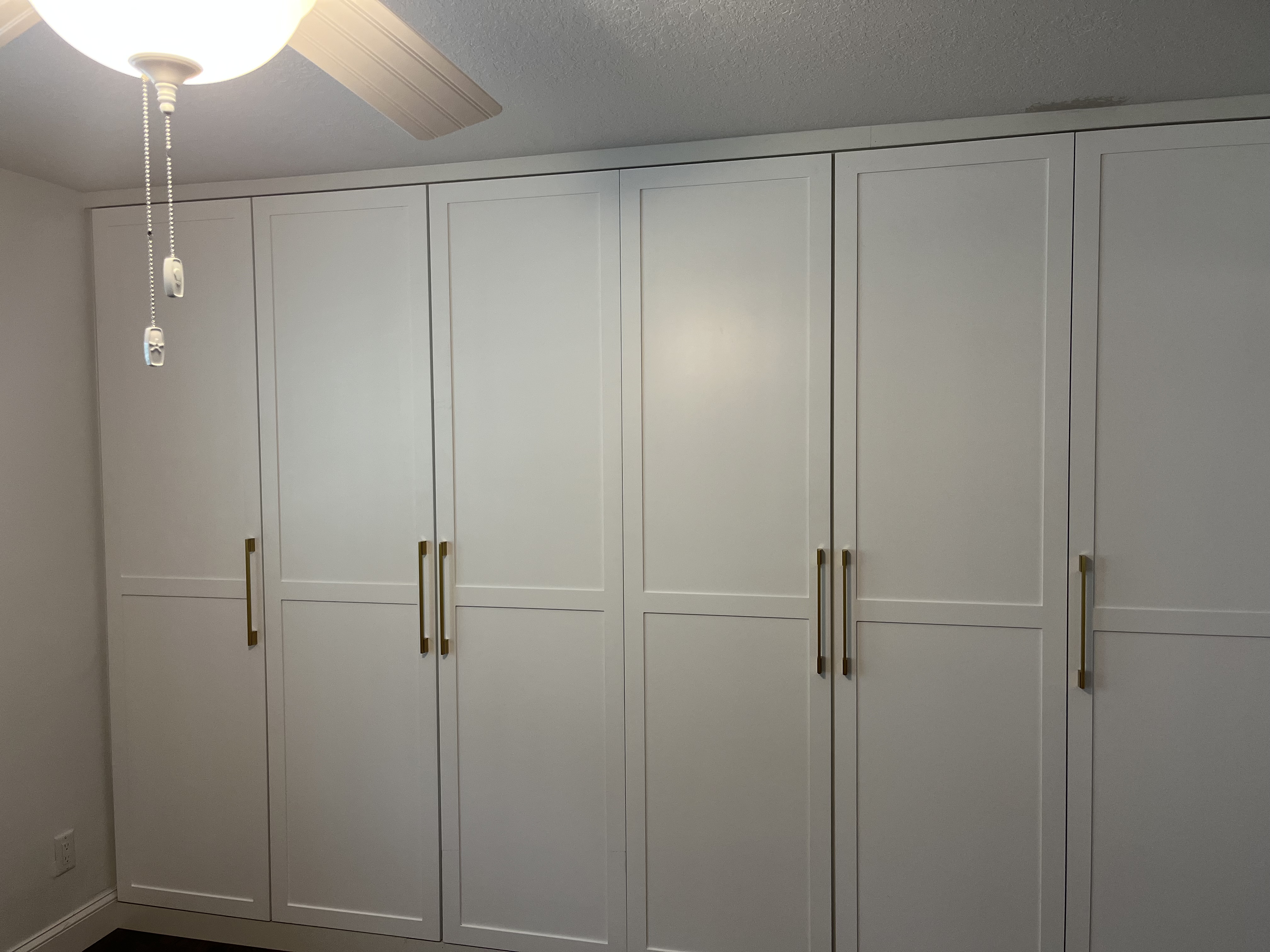 After photo of the finished custom closet with white doors and gold hardware