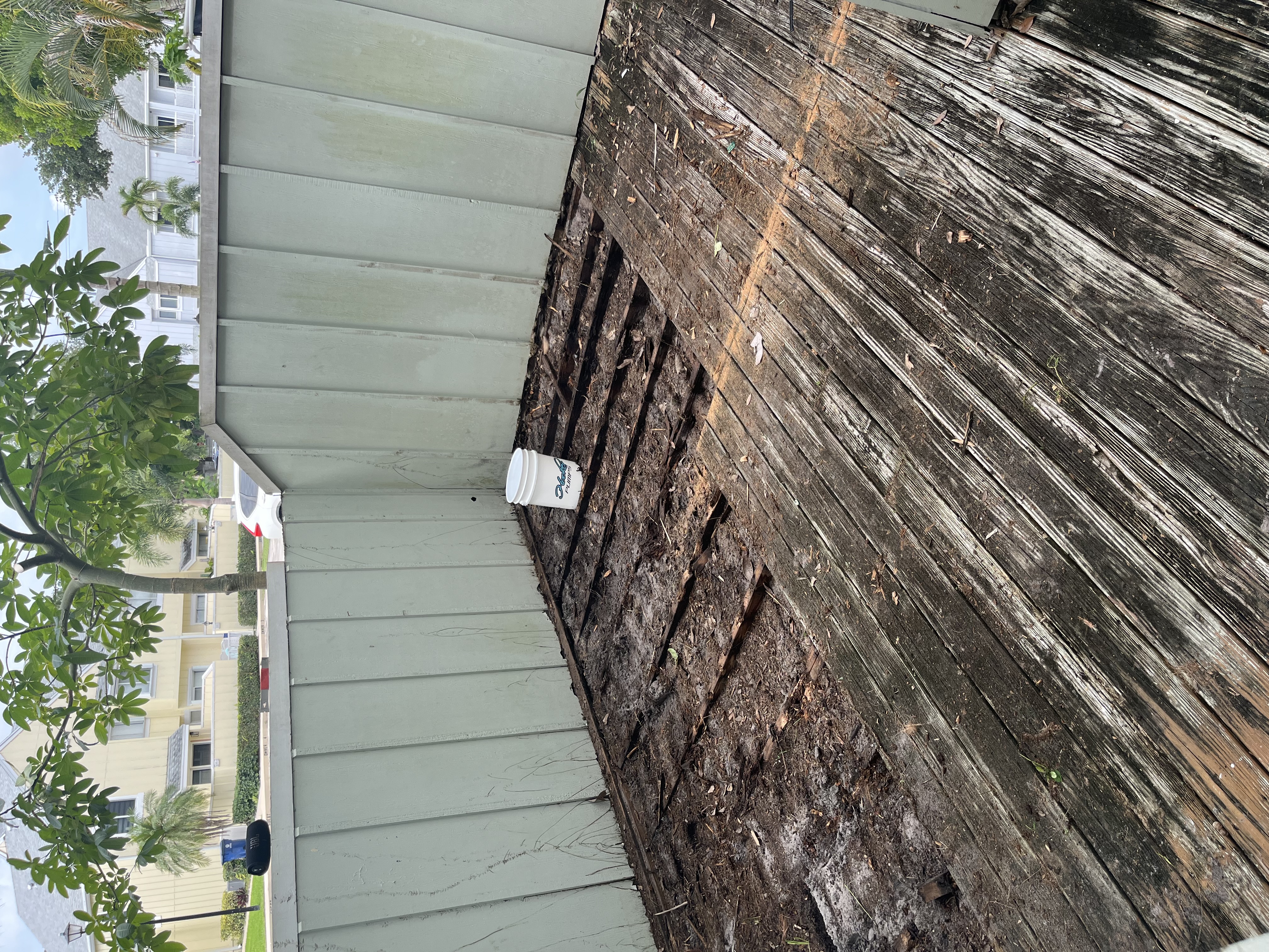 Backyard deck partially removed with framing and damaged boards exposed during demolition