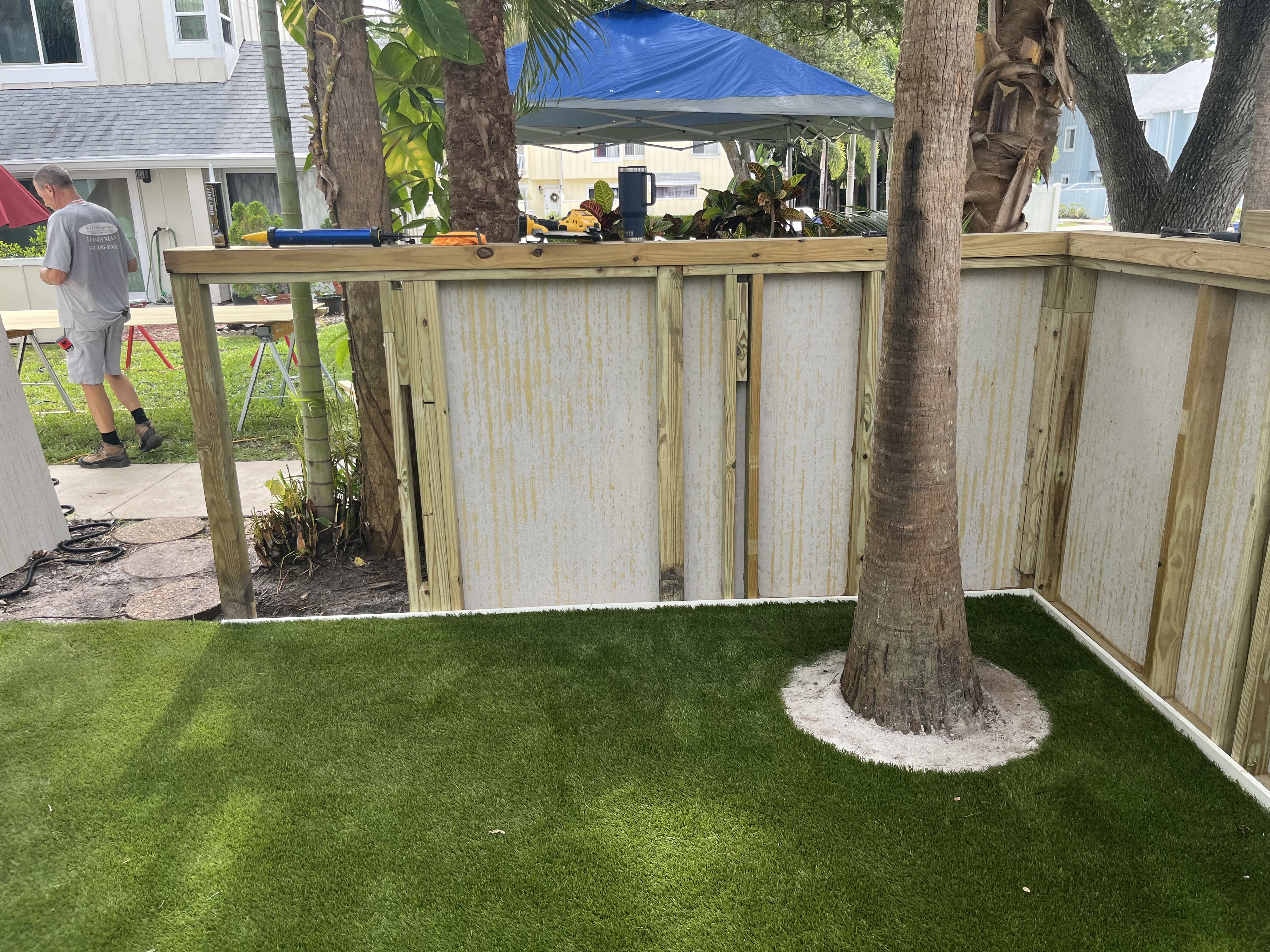 Finished artificial turf and fence detail around the tree after installation