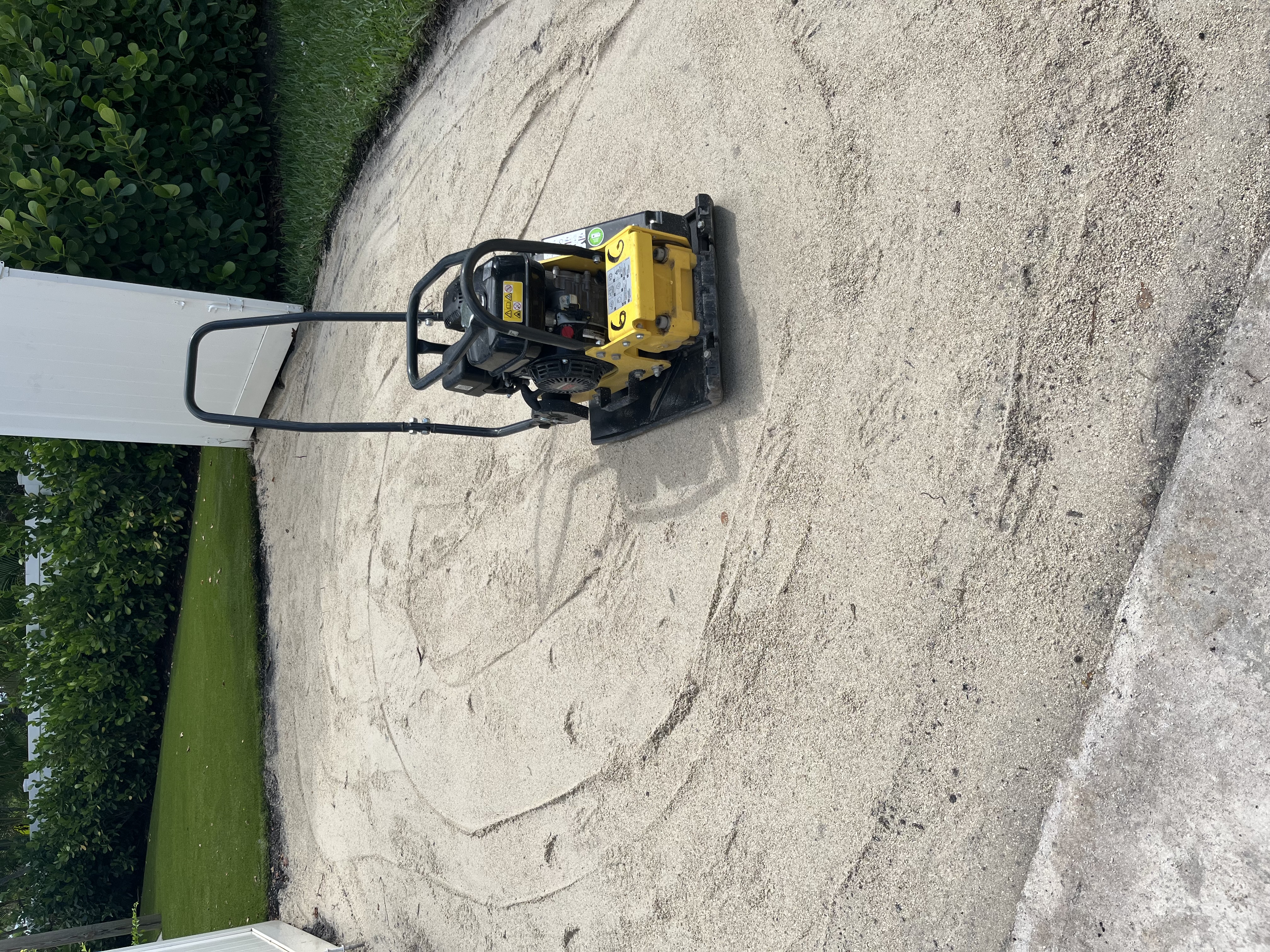 Compacted base material being leveled in the side yard area during preparation