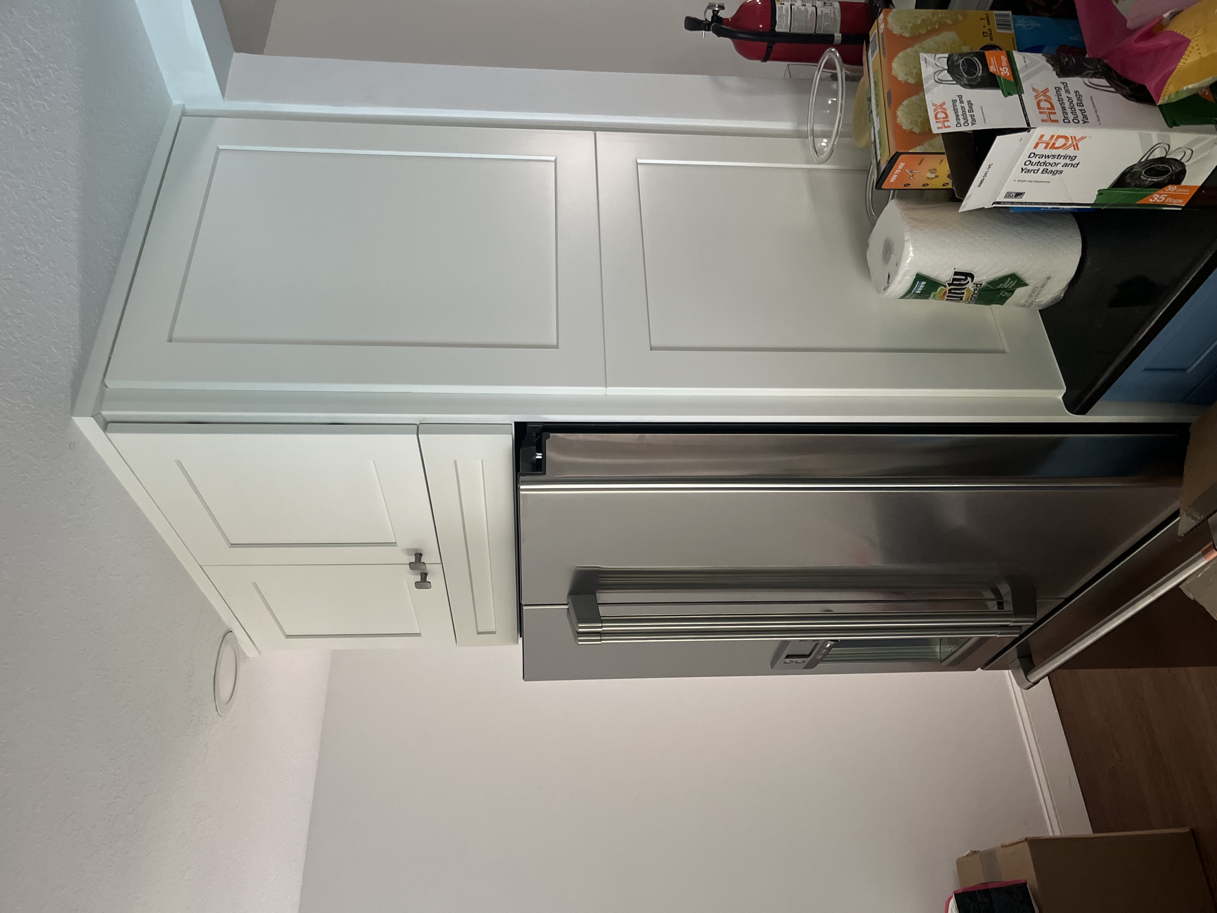 Finished tall pantry-style kitchen cabinet installation beside a stainless steel refrigerator
