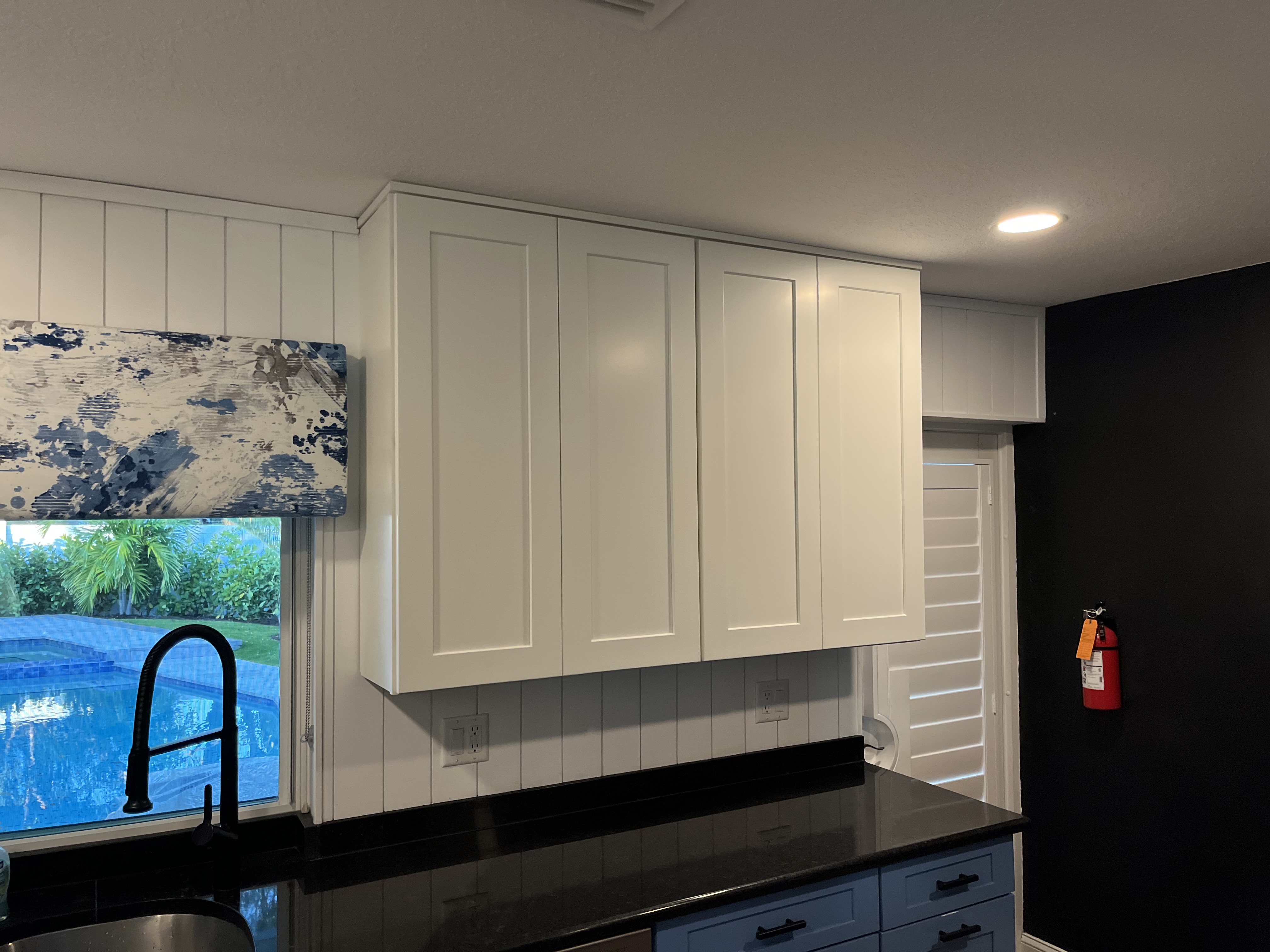 Finished side angle of the kitchen showing completed upper cabinetry and wall paneling