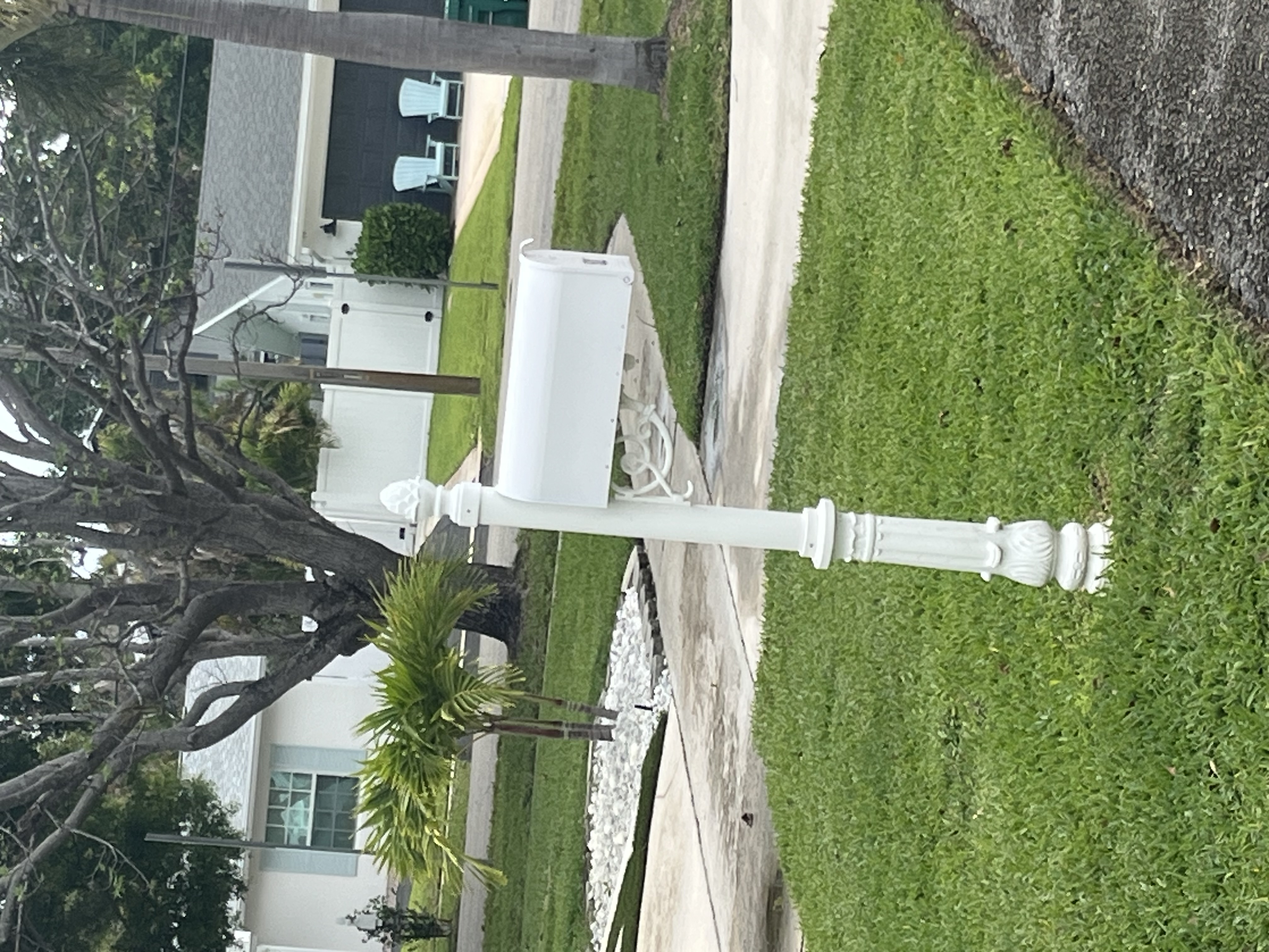 Finished white decorative mailbox post installed beside a residential driveway