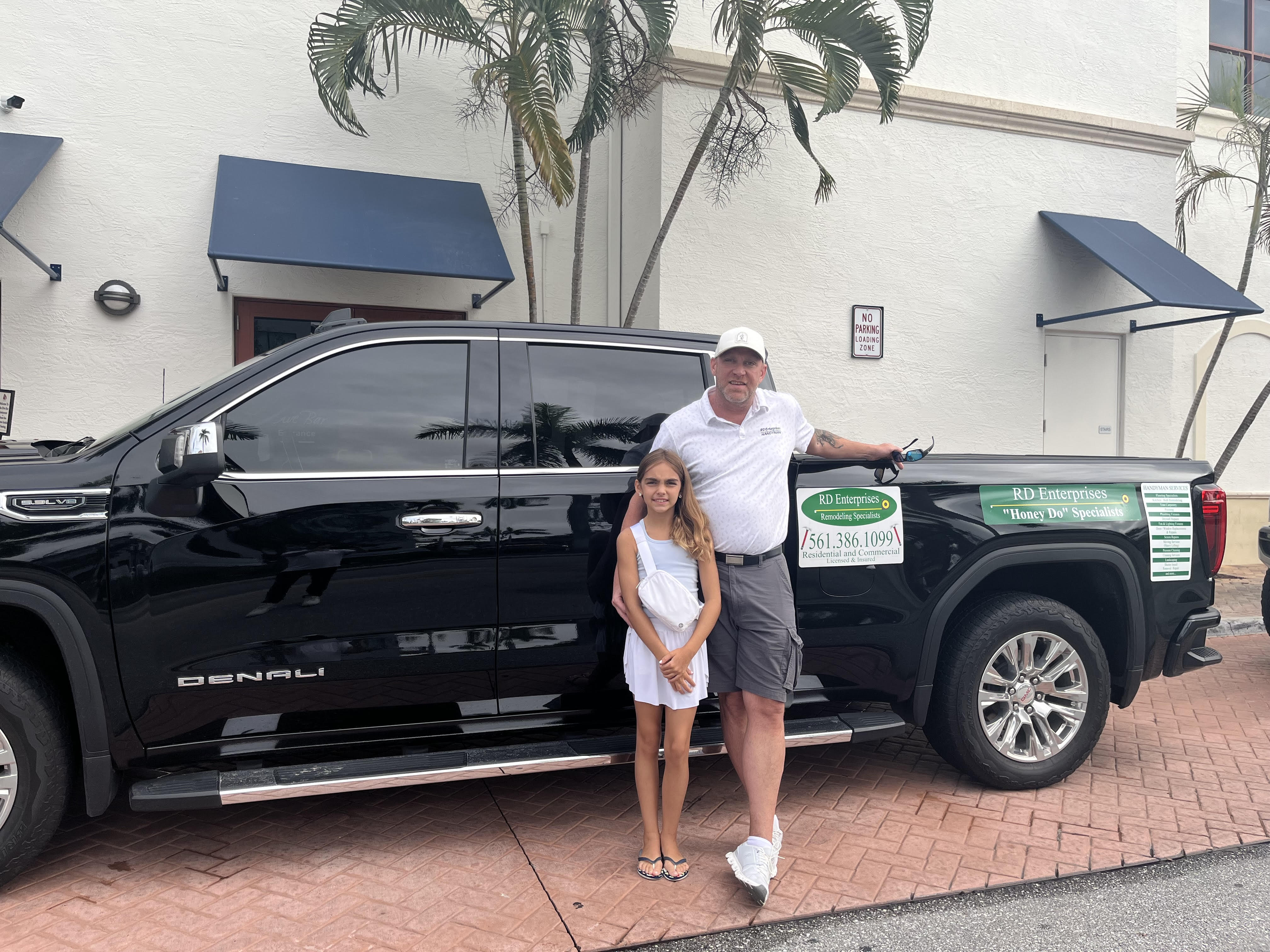 Russell Dusenbury standing with his daughter beside the RD Enterprises truck