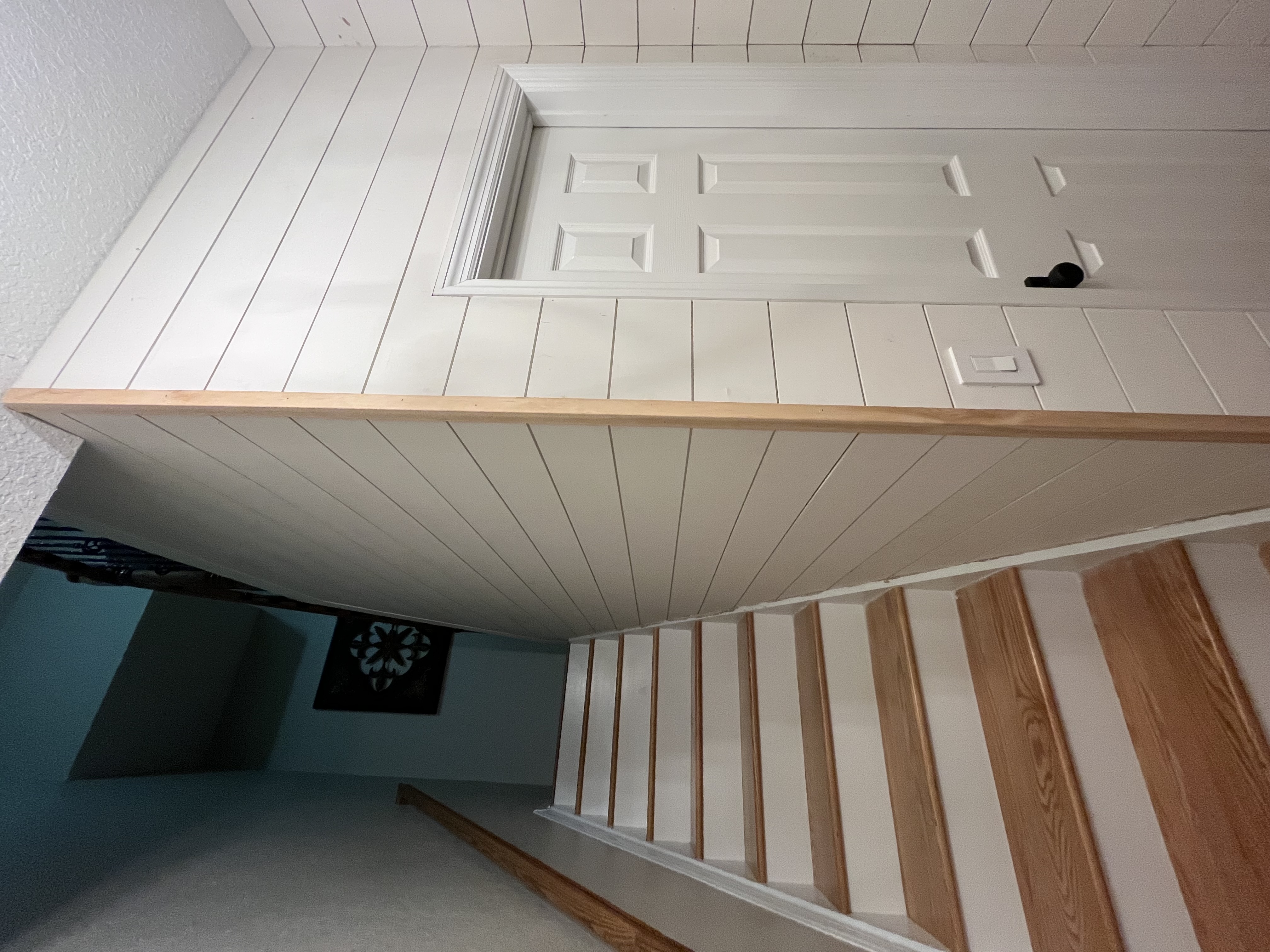 Finished stairwell wall paneling with clean white trim and wood flooring visible