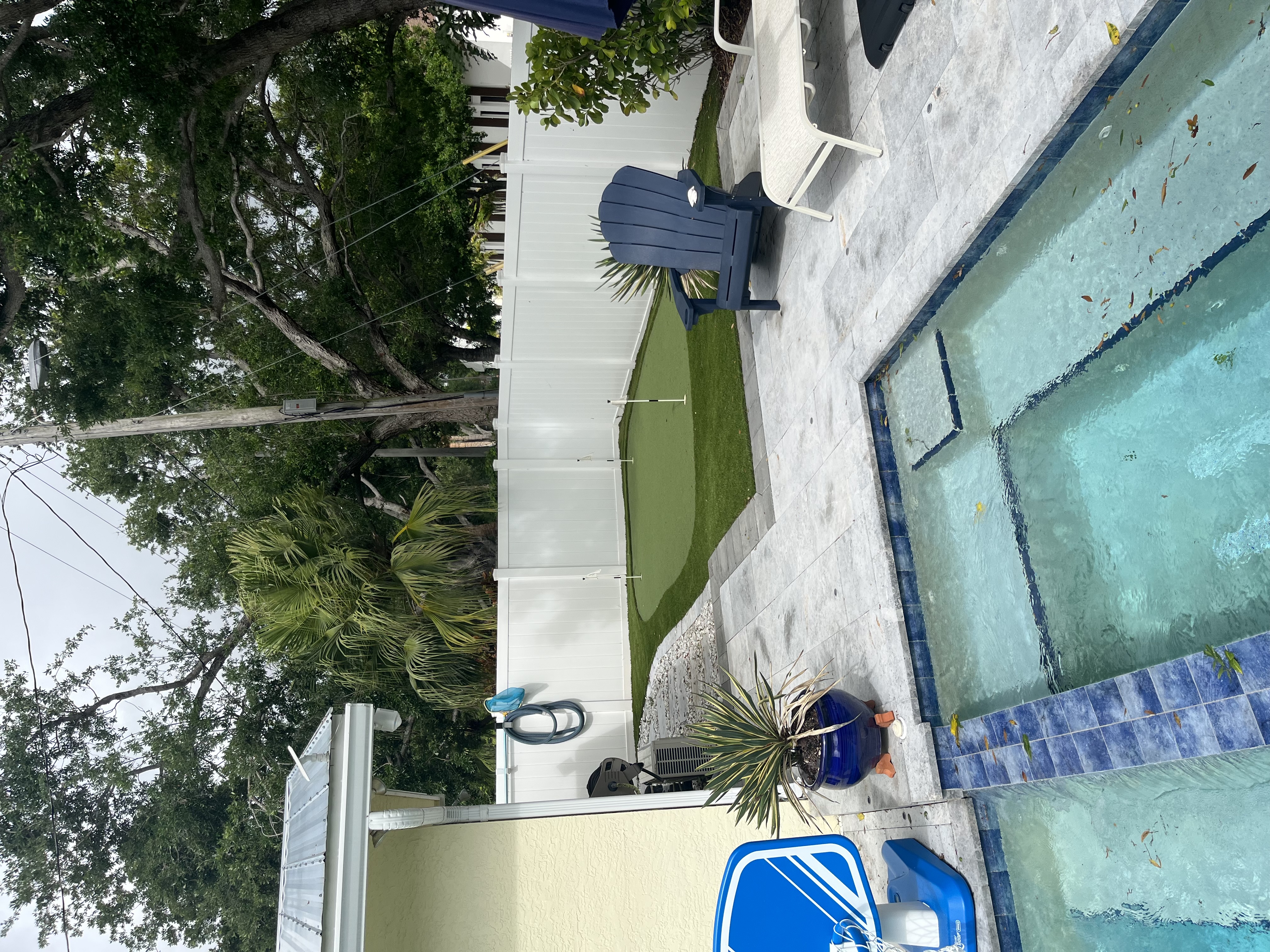Finished artificial turf lawn installed along a white fence next to a pool area