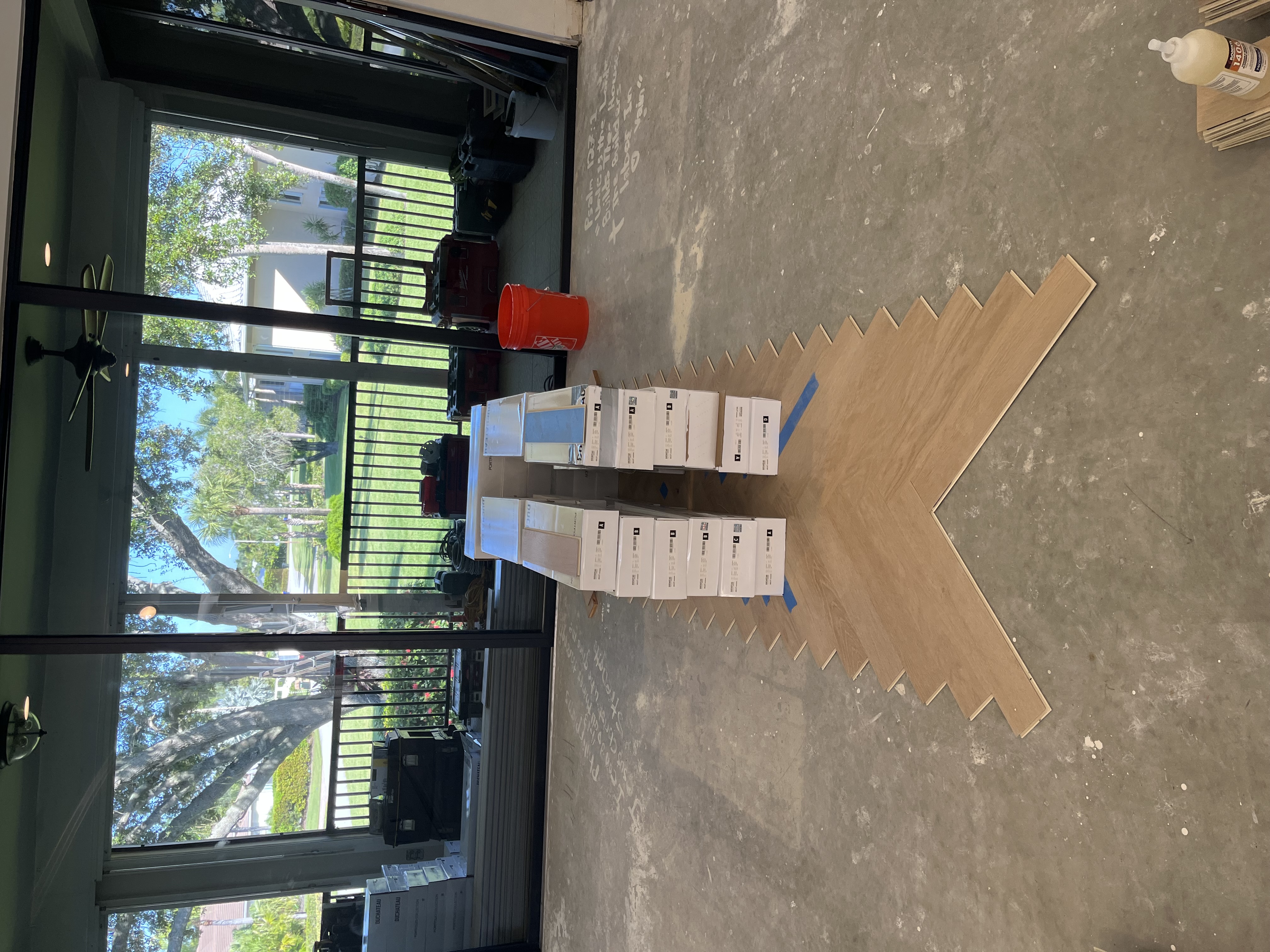 After photo of the room with new light wood herringbone flooring installed